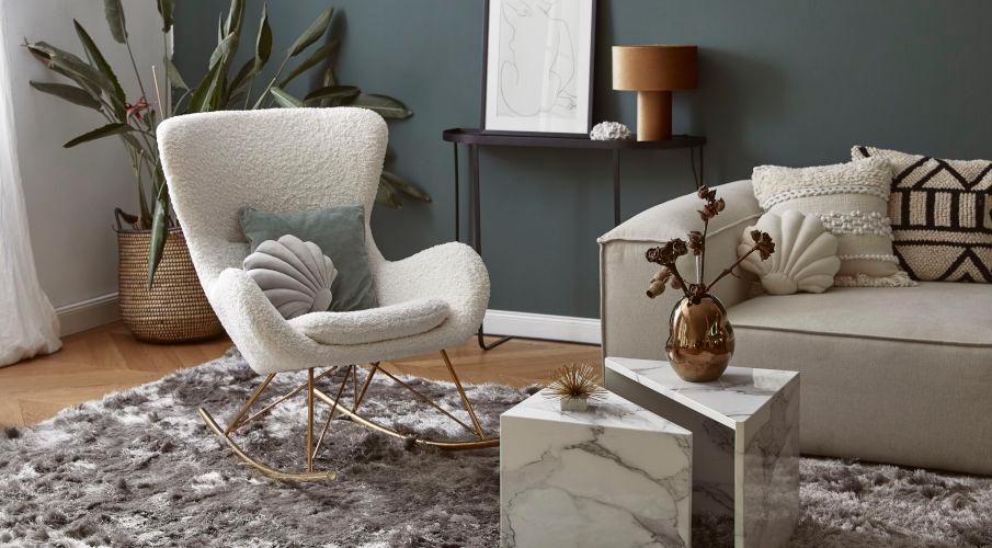 schelpen kussen op een witte fauteuil en naast een grijze bank