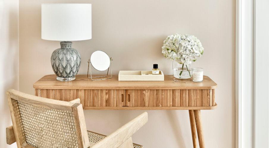 Smal bureau van hout met een lamp, vaas met bloemen en een houten stoel
