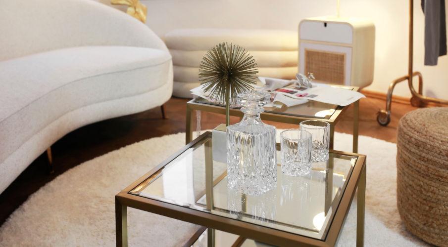 Glazen bijzettafel met een goud randje naast een ronde witte bank