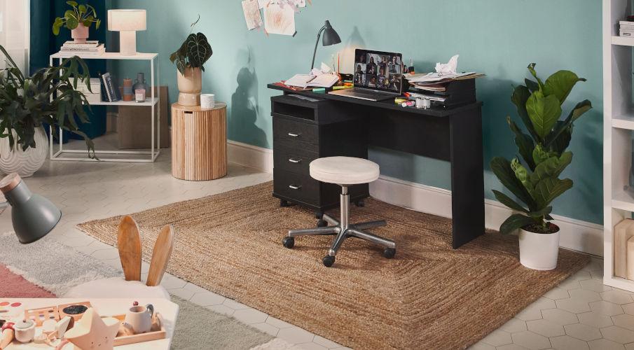 Kruk op wielen bij een zwart bureau en blauwe muur