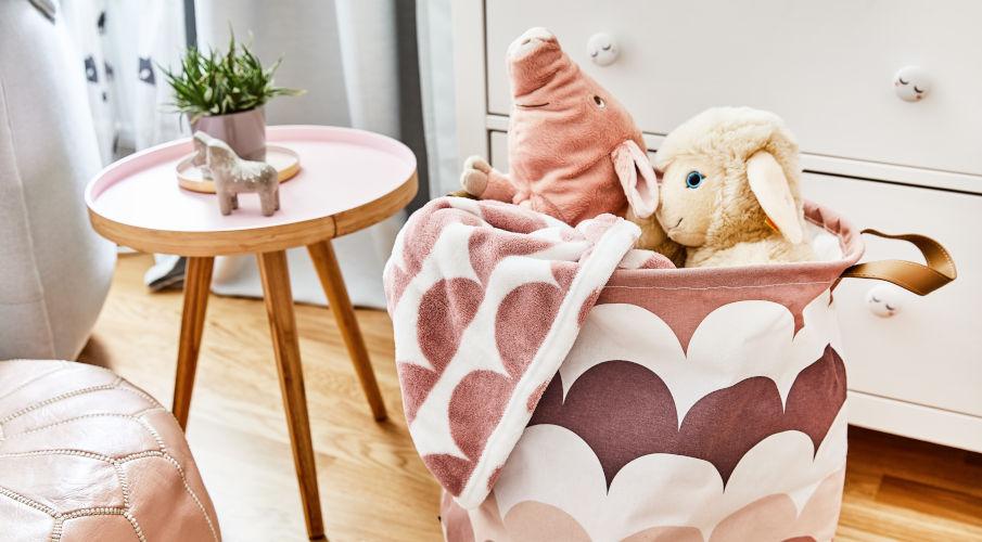 Speelgoed opberger in roze met knuffels er in en naast een houten tafeltje