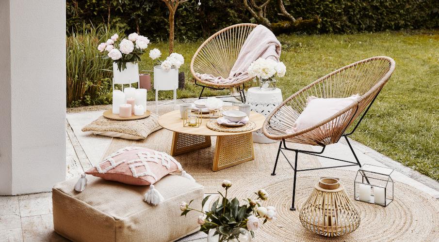Plantenbakken met houten tafel, rotan stoelen en roze textiel