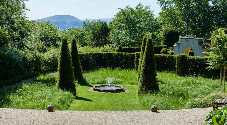 Fontein in de tuin tussen vier bomen