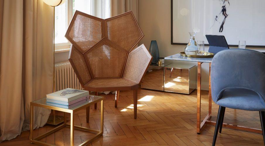Rieten fauteuil naast een raam met beige gordijnen