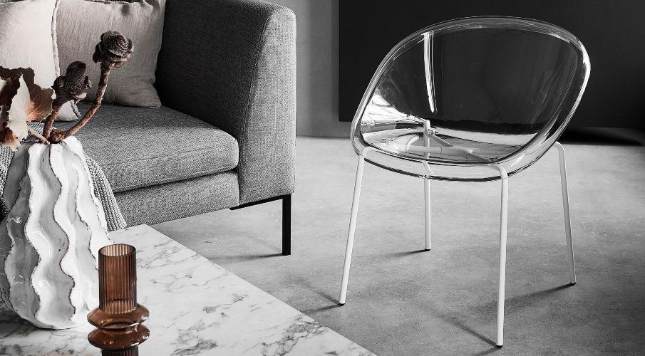 fauteuil industrieel van plastic in een woonkamer met grijze bank en marmeren salontafel