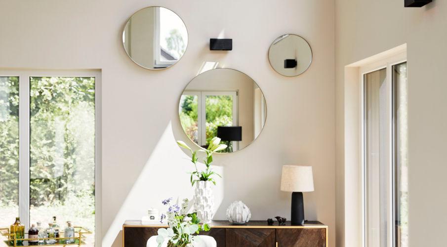 grote ronde spiegels aan de muur boven een houten dressoir