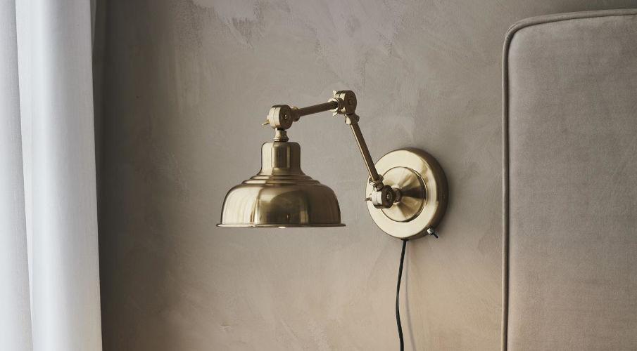 wandlamp met schakelaar in goud op een grijze muur