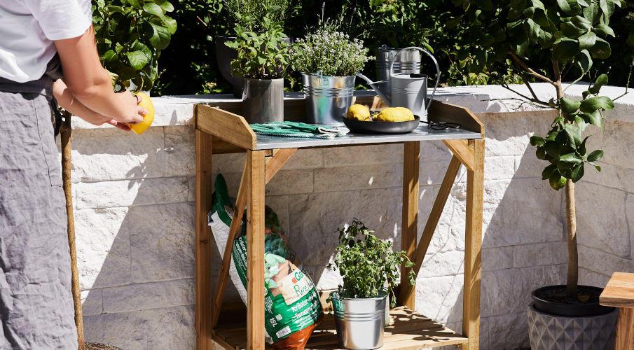 tuin etagere met plantenpotten naast een wit muurtje