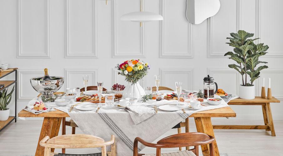 grote eettafel van hout met witte tafeldecoratie en bloemen