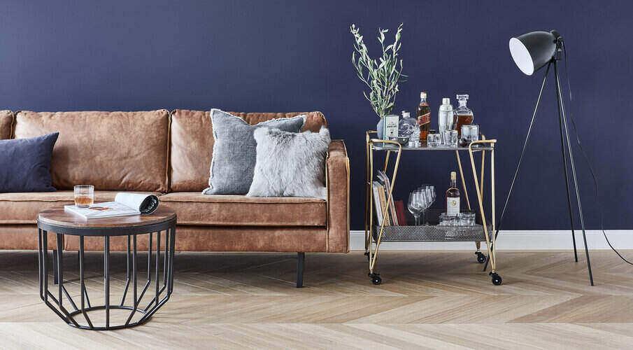 Sofy dwuosobowe Skórzana sofa stojąca pod granatową ścianą