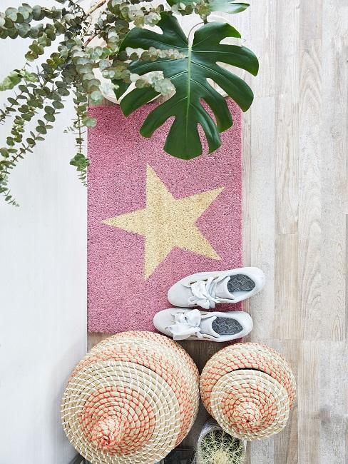 Chaussures blanches sur paillasson rose avec une étoile jaune au centre, entouré d'accéssoires de décoration