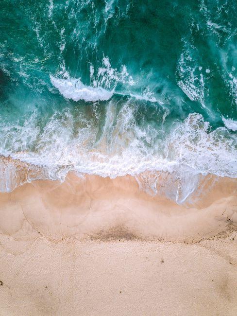 cosa portare al mare mare visto dall'alto con onde sulla spiaggia