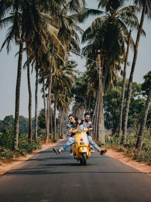viaggio di nozze coppia in vespa su viale con palme