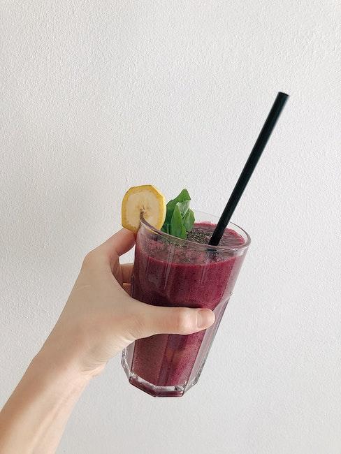 estratti di frutta e verdura mano che tiene bicchiere con estratto di colore rosso scuro