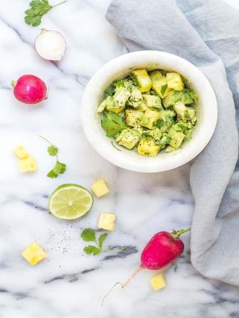 Salsa guacamole z białej miseczke na marmurowym blacie