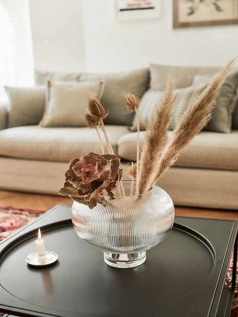 Vase sur table d’appoint avec canapé beige à l’arrière Vase décoré sur table d'appoint