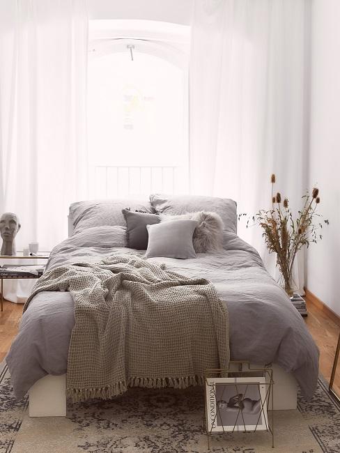 Schlafzimmer mit grauer Bettwäsche aus Leinen und Kissen