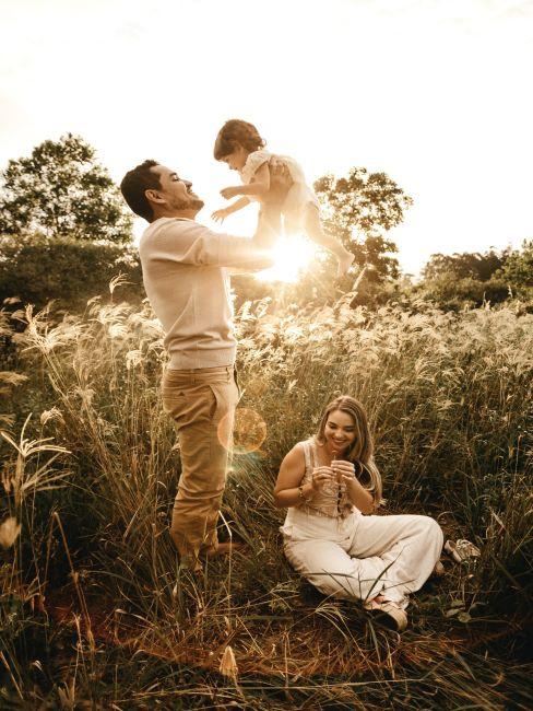 cadeau pour papa famille dans un pre, mama assise par terre, papa porte l enfant