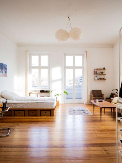 studio-banner grand espace ouvert, parquet, planchers en bois, grandes fenetres, murs blancs, lumineux, chambre a coucher et coin salon dans la meme piece