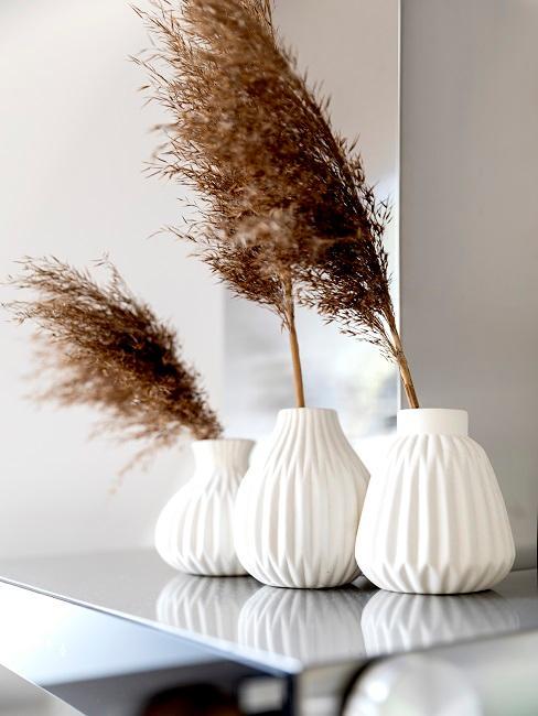 Sécher l’herbe de la pampa trois vases blancs sur une table avec de l'herbe de la pampa