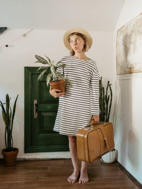 cosa mettere in valigia ragazza con vestito a righe con valigia di pelle