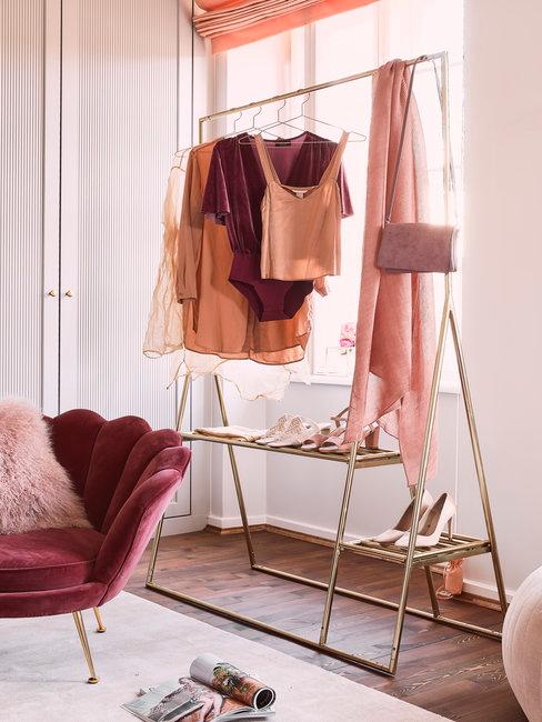 AFW kledingrek Gouden kledingrek met roze en nude tinten op houten vloer met vloerkleed en roze stoel