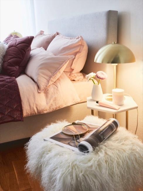 Cama en tonos rosados con mesilla de piel sintética blanca