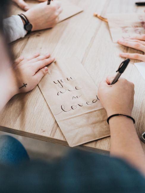 aprender-caligrafia Mano de hombre escribiendo en caligrafía sobre bolsa de papel