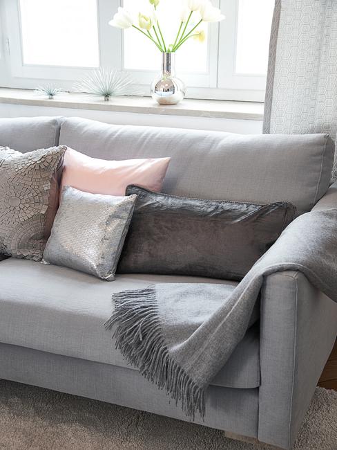 Canapé gris avec plaid et coussins en tons pastels