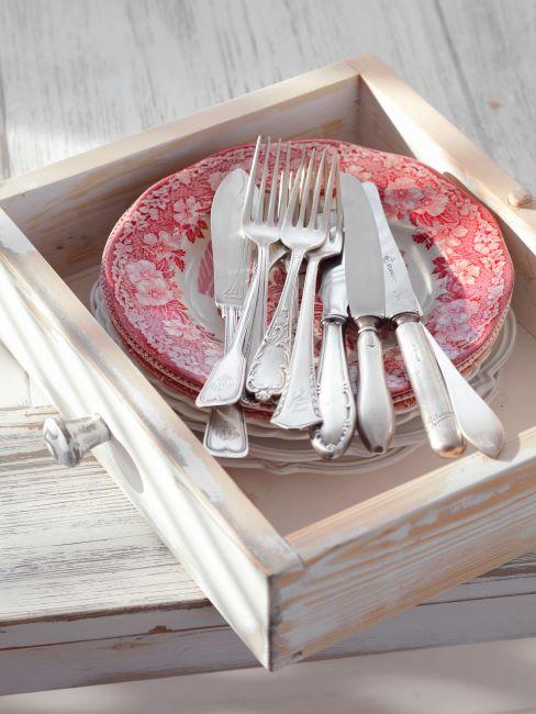 Les assiettes assiettes élégantes à bord orné à motif rouge, avec ménagère argentée posée dessus
