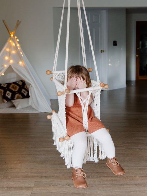 luminaires-chambre-bebe petite fille dans une balancoire, derriere elle un tipi avec guirlande lumineuse