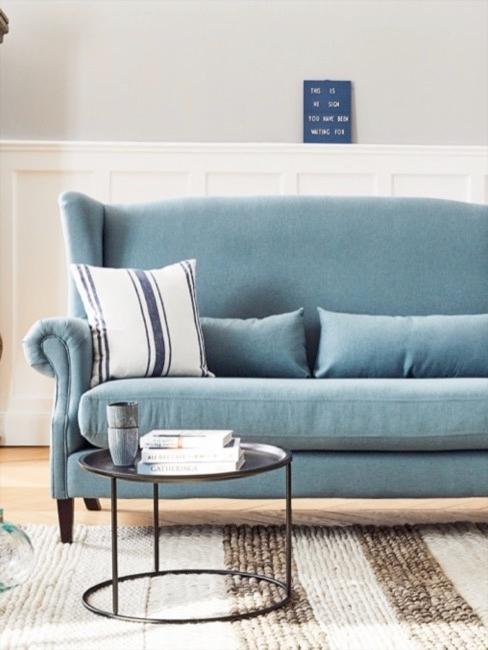 Niebieska sofa z poduszkÄ
w paski, pasiasty dywan i maÅy metalowy stolik kawowy