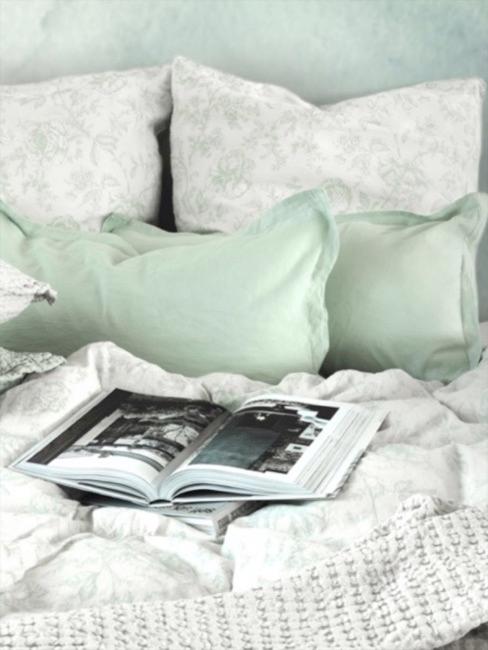 Bett mit floraler Bettwäsche und grünen Kissenbezügen