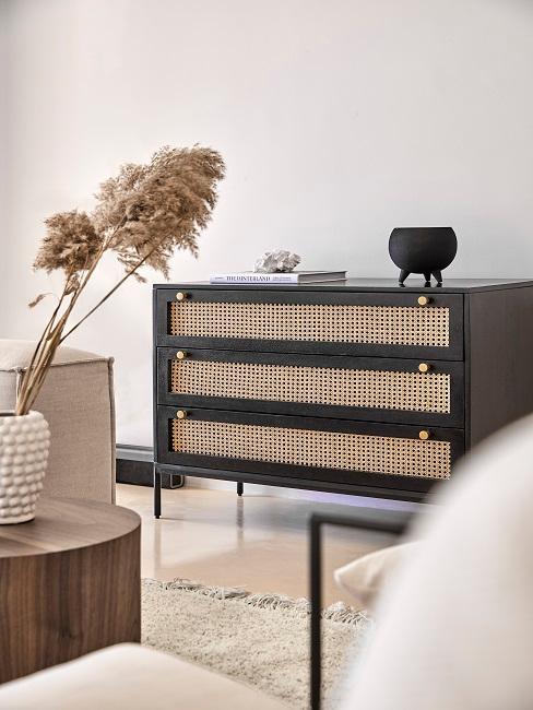 Schwarze Kommode mit Geflecht in hellem Wohnzimmer