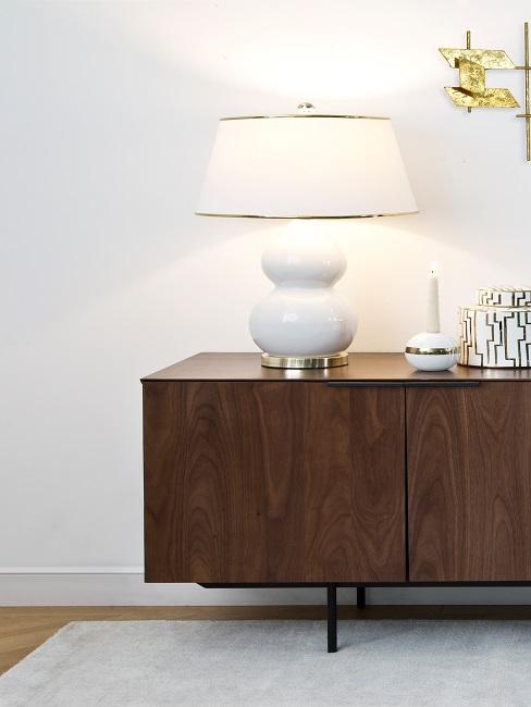 Große weiße Lampe mit Keramikfuß auf braunem Sideboard