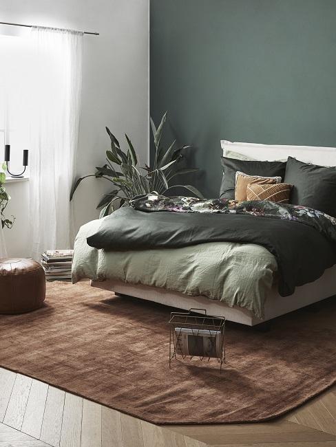 Grüne Wandfarbe im Schlafzimmer kombinieren mit braunem Teppich, grüner Bettwäsche und Pflanzen