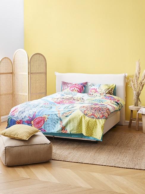Gelbe Wandfarbe im Schlafzimmer kombinieren mit bunter Bettwäsche und Wohnaccessoires aus Naturmaterialien