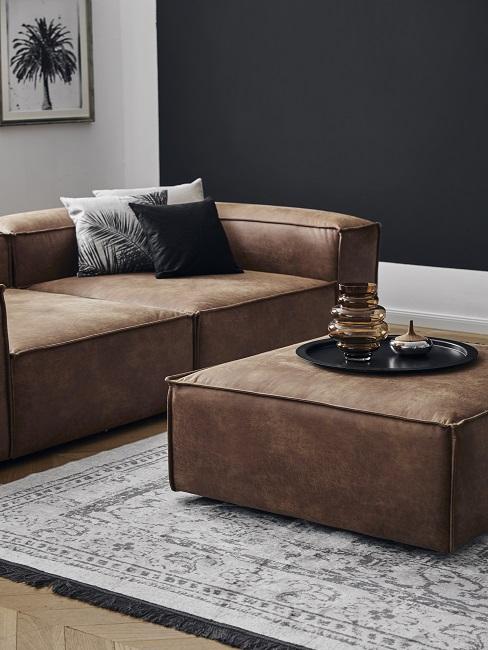 Wandfarbe Schwarz kombinieren mit braunem Ledersofa, grauem Vintage-Teppich und schwarz-weißen Kissen