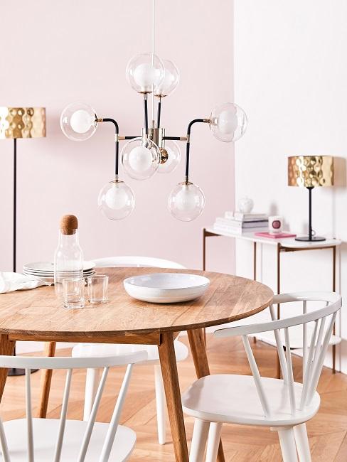 Pastellrosa Wand im Esszimmer mit Holztisch, weißen Stühlen und großer Pendelleuchte