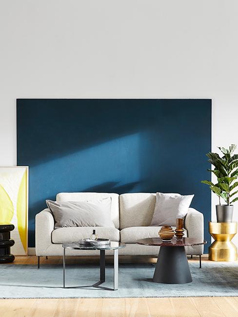 bauhaus Canapé beige avec mur bleu foncé et cadre jaune citron, tables basses noires