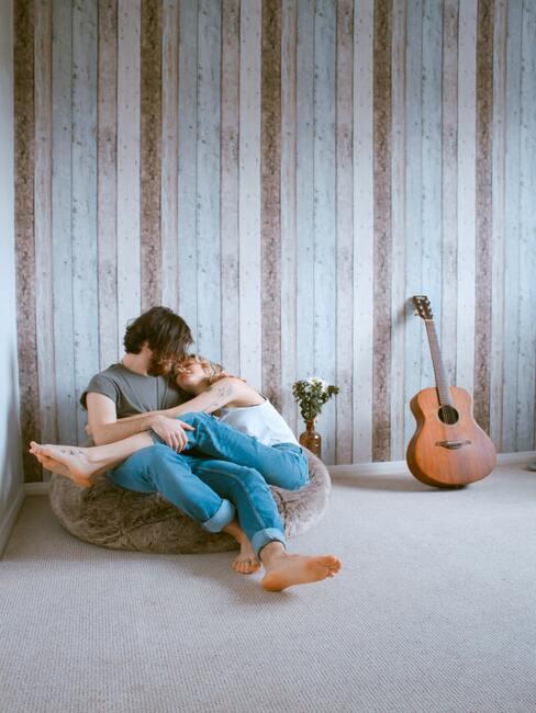 toa-heftiba-yZDYBogsWEc-unsplash Couple qui se fait un câlin installé sur un pouf avec une guitare