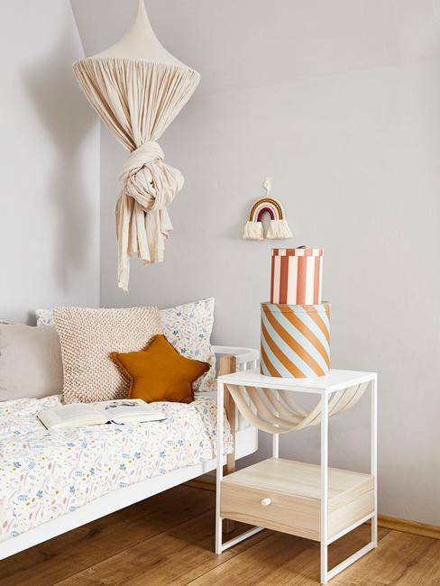 Kinderkamer inspiratie Wit beddengoed met een stippenpatroon en kussens naast een wit nachtkastje met dozen