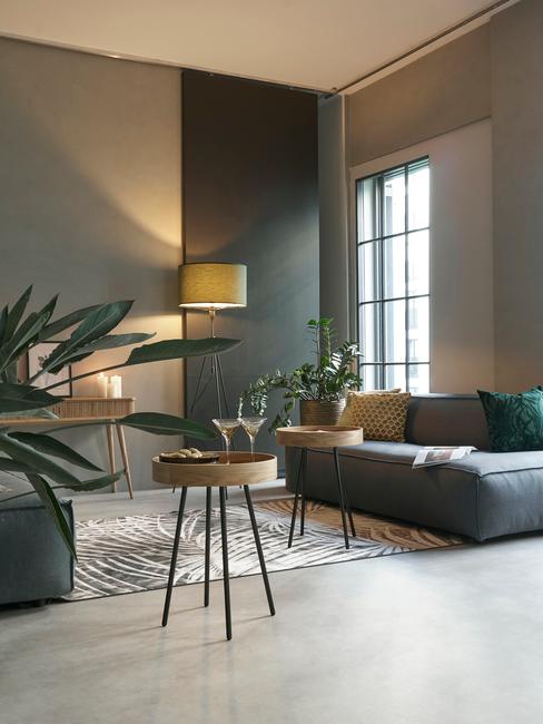 Salon w stylu industrialnym z ciemnymi ścianami, czarną sofą, metalowymi stolikami oraz dekoracjami