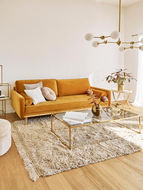 Jasny salon w stylu retro ze szklanym stolikiem kawowym, lampą oraz pomarańczową sofą