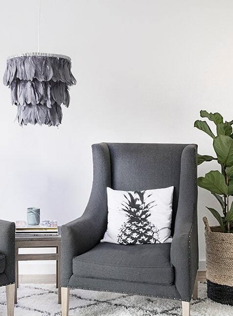 Wnętrze salonu z szarym fotele z poduszką, dywanem i lampą DIY w stylu boho