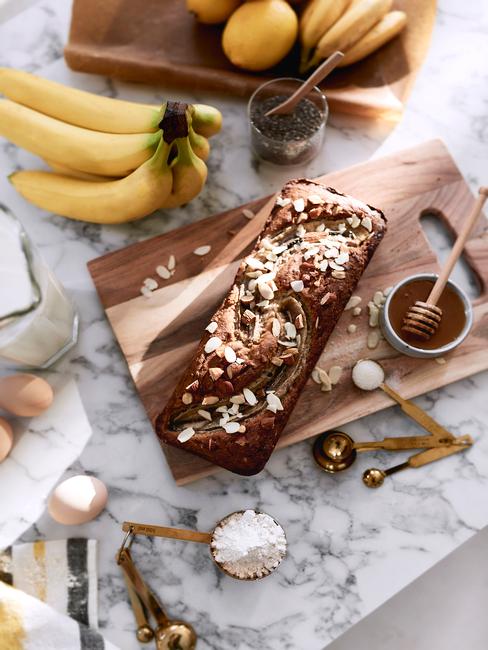 chlebek bananowy Chlebek bananowy na drewnianej tacy w na marmurowym blacie z obok skadnikw potrzebnych do jego wykonania