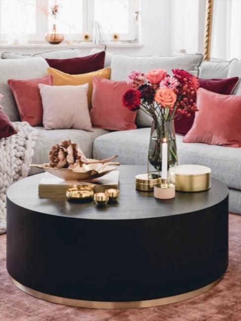 Salón con sofá gris, cojines en tonos coral y mesa auxiliar con decoraciones doradas