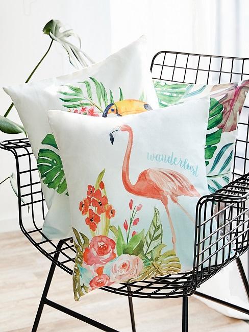 Kissen mit Flamingo Druck auf einem schwarzen Stuhl