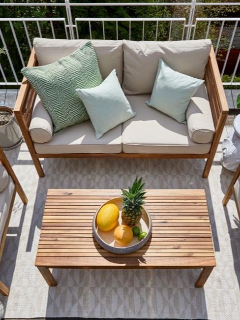 decorar balcón sofá con cojines azules y mesa de centro de madera en un balcón