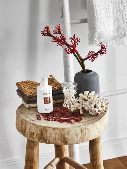 Badezimmerpflanzen Deko-Zweig auf Holzhocker neben Kosmetik als schöne Baddeko